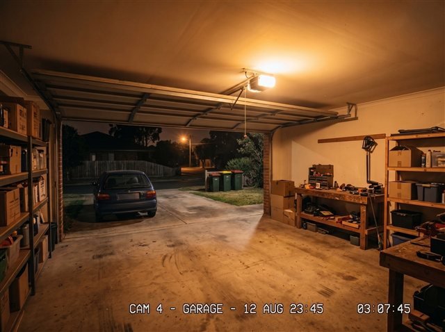 Camera view from inside the garage, looking out at the driveway